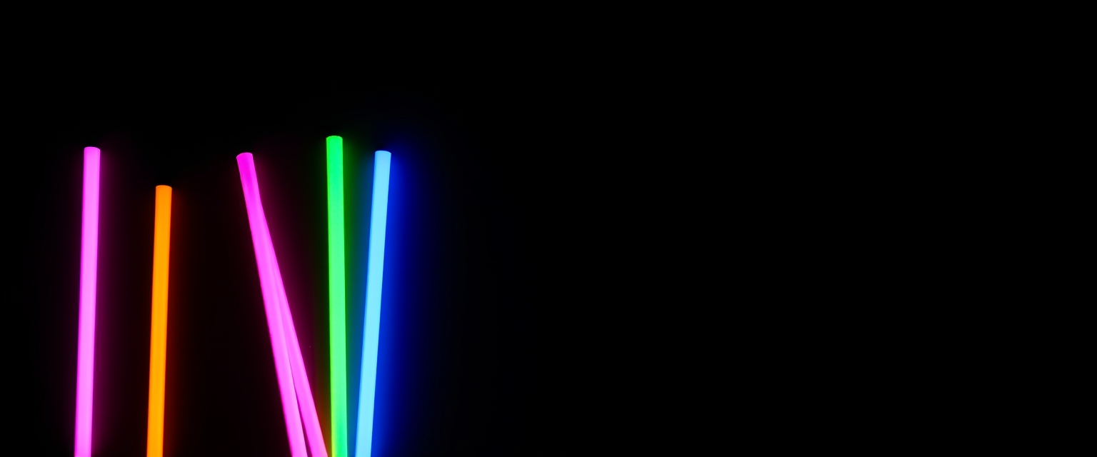 A group of colorful neon sticks on a black background. - Image